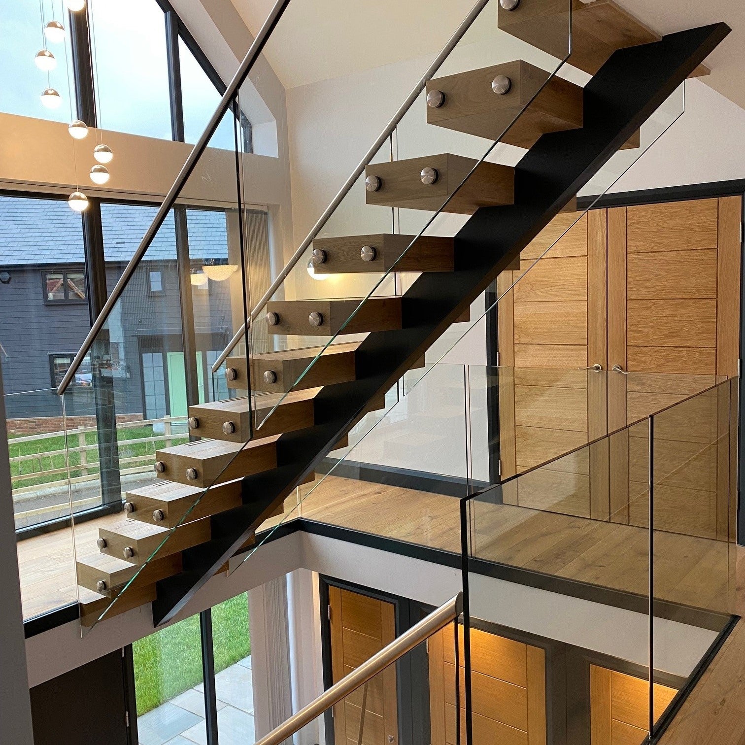 Fully fabricated central spine staircase, with custom made wraparound oak treads, concealing all the structural connections. Design also includes 15mm structural glass as a frameless balustrade, secured with stainless steel fixings, and capped with a stainless steel handrail. As per the clients request, we also modified the treads to include anti-slip bars. Project installed within a timber frame new build in Dunmow, Essex