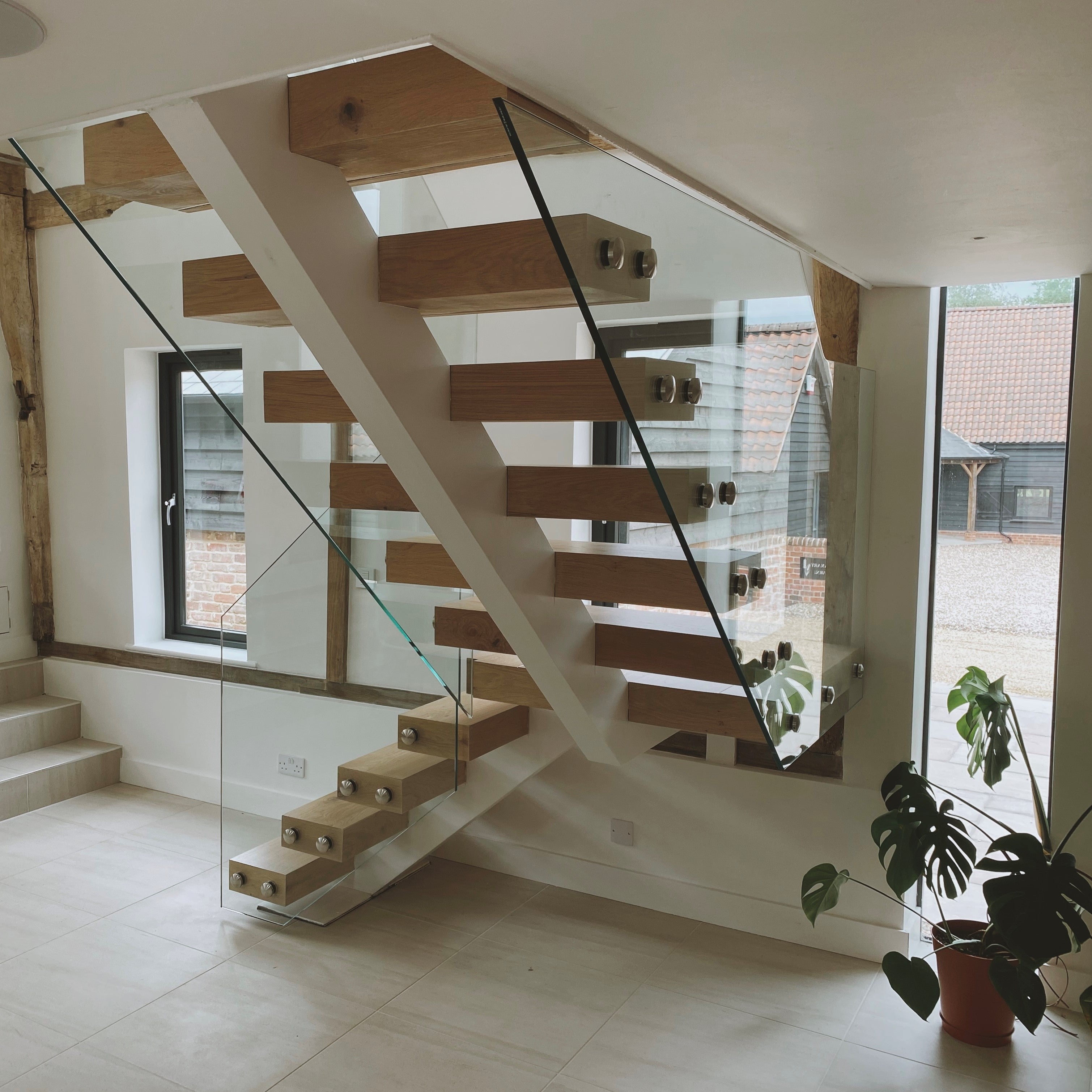 Fully fabricated central spine staircase, with custom made wraparound oak treads, concealing all the structural connections. Design also includes 15mm structural glass as a frameless balustrade, secured with stainless steel fixings. Project installed within a barn conversion in Essex