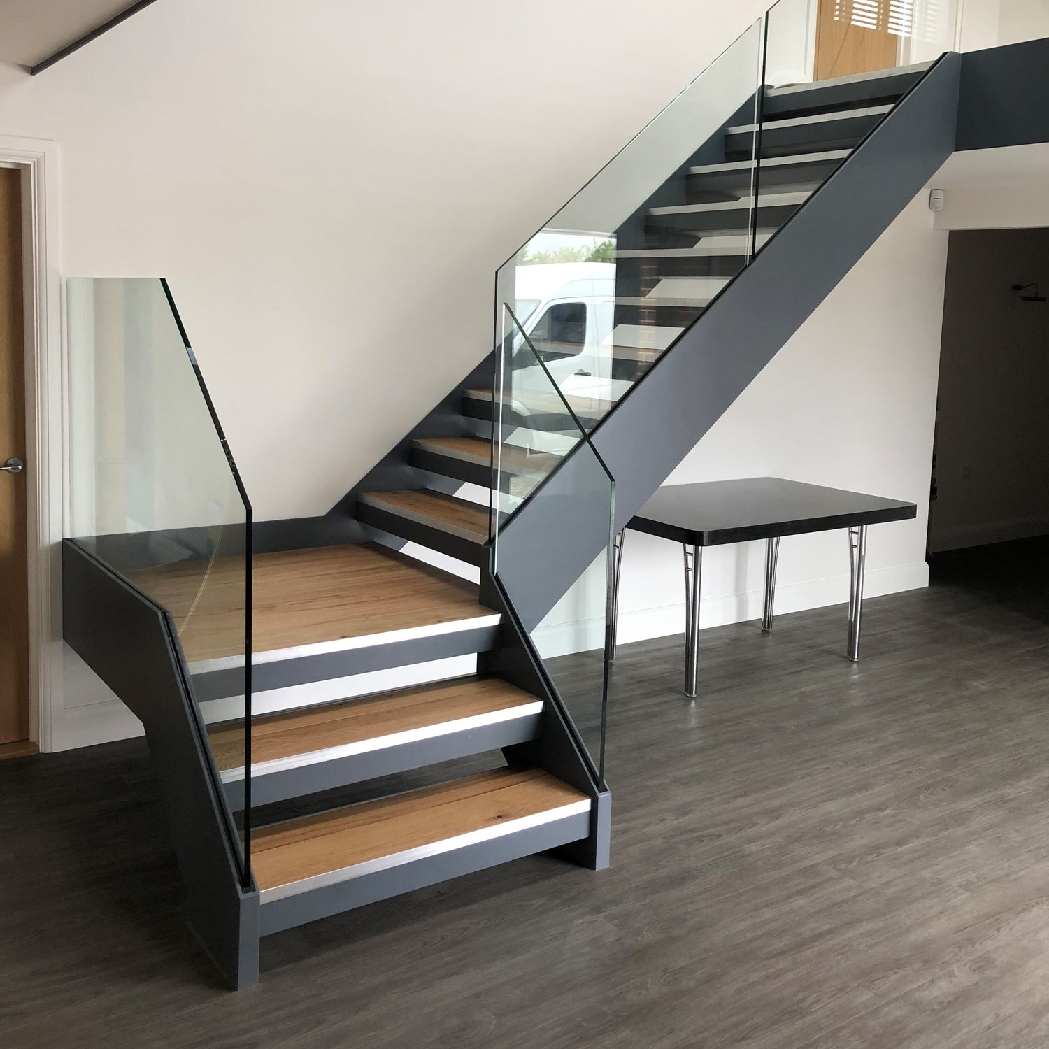 Painted finish channel stringer with frameless glass balustrade. Metal feature staircase