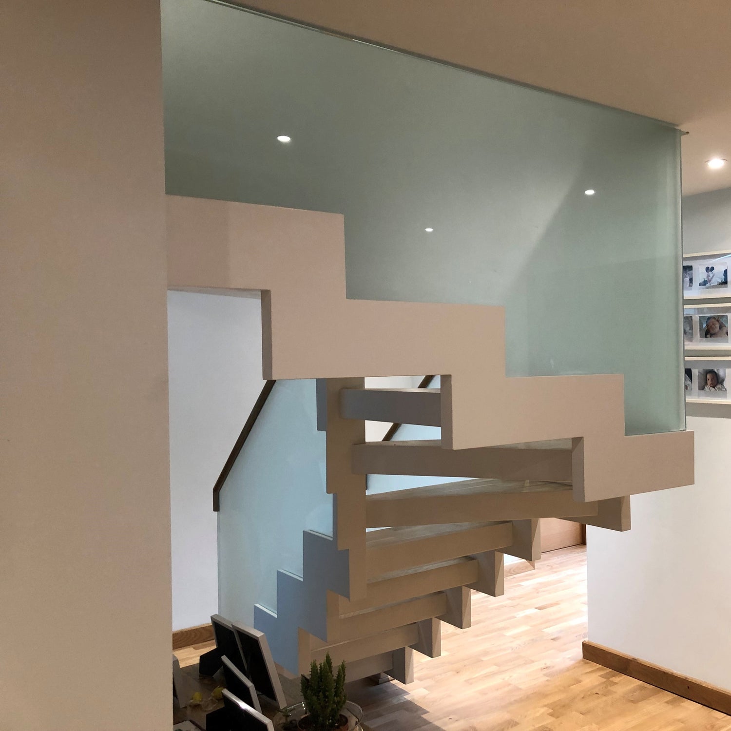 Feature staircase in metal. Zig-zag design channelled stringer with frosted glass balustrade for privacy. Painted white with oak tread finishes